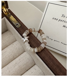 Detail of beaded star ring with ivory and amber beads on a wooden jewelry box