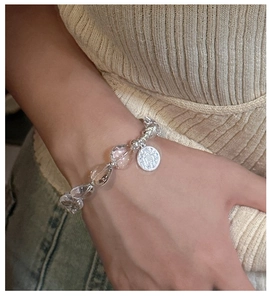 Detail of beaded bracelet with clear crystal hearts and vintage relief pendant on wrist