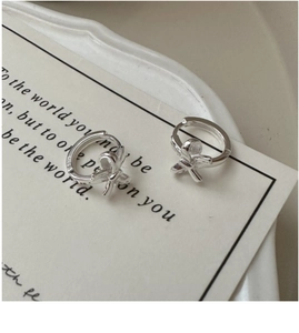 Close-up of S925 sterling silver bow earrings showing the hallmark on a ceramic plate