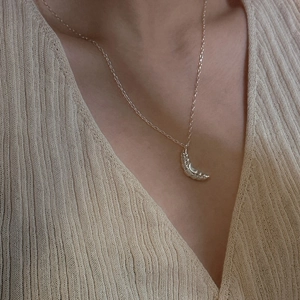 S925 sterling silver croissant pendant necklace styled on a model over beige knitwear
