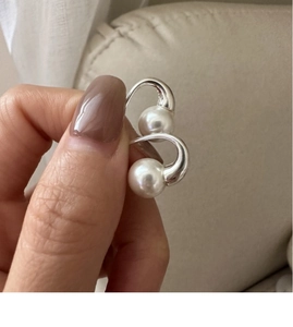 Detailed view of S925 sterling silver earrings with glossy white pearls held by hand