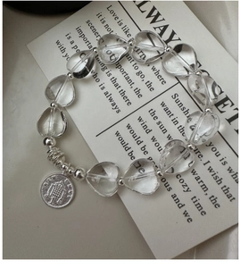 Detail of S925 silver heart crystal bracelet with vintage coin charm on aesthetic background