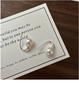 Detail shot of elegant S925 silver pearl drop earrings on a vintage paper background