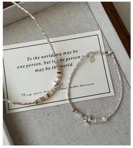 Macro detail of S925 silver star necklace and bracelet set on beige fabric tray