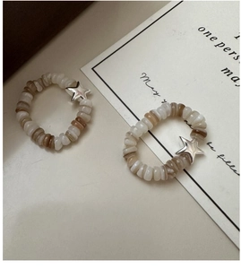 Macro detail of elastic beaded rings with silver star charms and natural stone texture
