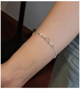 Detail view of S925 sterling silver star bracelet with delicate pearls on female wrist