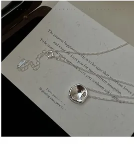 Macro shot of silver irregular concave square pendant on delicate O-chain necklace