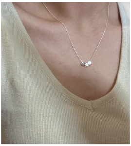 Close-up of a minimalist S925 sterling silver necklace with three small lettered beads