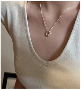 Detail shot of a S925 sterling silver irregular pendant on a minimalist necklace worn by a model