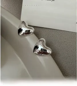 Macro detail of polished S925 sterling silver heart stud earrings on a ceramic dish