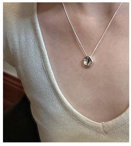 Macro view of a minimalist S925 silver necklace with an irregular pebble pendant