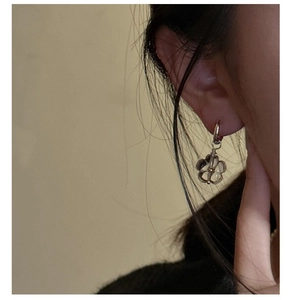 Close-up of S925 silver daisy earrings with translucent resin petals on a model's ear