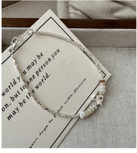 Macro detail of S925 sterling silver star pendant bracelet with white mother-of-pearl beads
