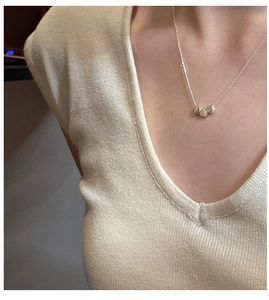 Close-up of three polished silver beads on a thin chain necklace worn by a model