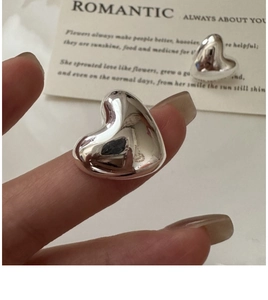 Macro shot of polished S925 silver heart stud earrings with a glossy mirror finish
