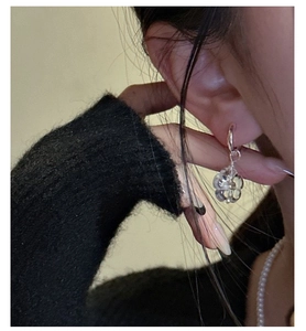 Close-up of minimalist S925 silver hoop earrings with clear resin daisy flower pendants