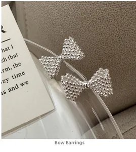 Detailed view of silver bow earrings with textured bead finish on glass rim