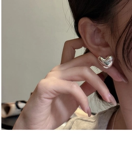 Close-up of minimalist S925 sterling silver heart stud earring on a model ear