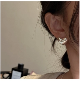 Close-up of polished S925 sterling silver heart stud earring worn on model's ear