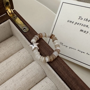 Handmade beaded ring with silver star charm displayed on a vintage wooden jewelry box