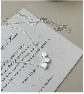 Macro view of S925 sterling silver necklace featuring three polished round discs on a fine chain