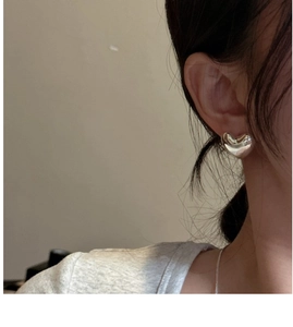 Close-up of minimalist S925 sterling silver heart-shaped stud earrings on a model ear