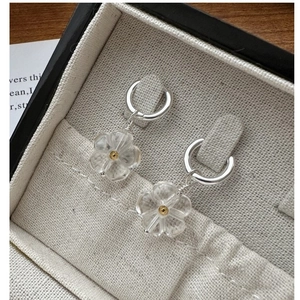 Macro shot of silver S925 earrings with transparent daisy charms on gray jewelry box
