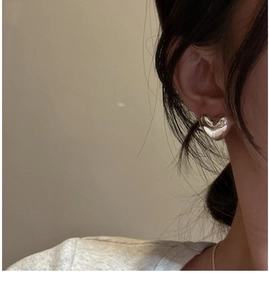 Close-up of minimalist S925 sterling silver heart studs worn on a model's ear
