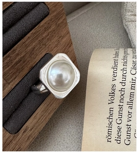 Macro detail of silver square mabe pearl ring on a vintage wooden jewelry stand