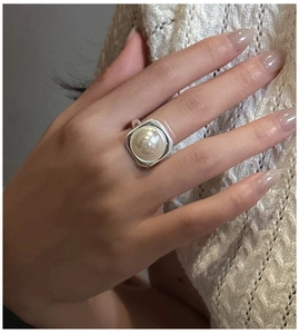Detail of a large Mabe pearl ring on silver square setting worn on model's finger
