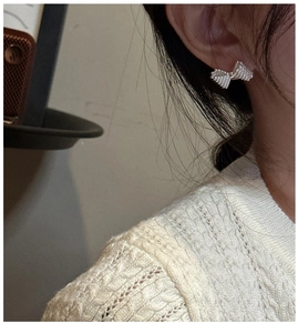Close-up of S925 silver bow stud earrings with textured finish on a model's ear