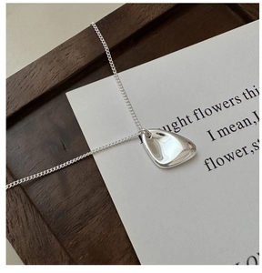 Gros plan d'un collier en argent S925 irrégulier avec une surface polie effet miroir