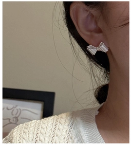 Detailed close-up of S925 silver bow earrings featuring a textured beaded finish