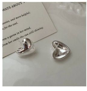 Detail of silver heart-shaped stud earrings with a high-polished mirror finish and back pin