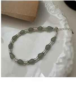 Détail du bracelet en argent S925 avec perles de pierre verte en goutte sur une assiette