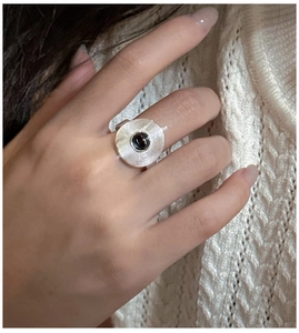 Macro shot of silver ring with record texture and black onyx inlay on knitwear