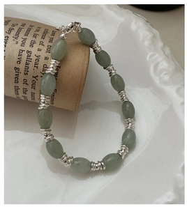Détail d'un bracelet en perles vintage avec pierres ovales vert clair et spirales argent