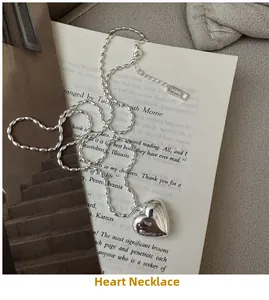 Detail of silver heart pendant on bean link chain showing AG325 hallmark and lobster clasp