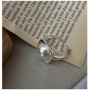 Macro detail of S925 silver ring featuring a large pearl on a vintage book page