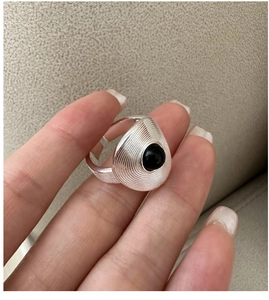 Macro shot of silver ring with brushed teardrop design and black onyx stone inlay
