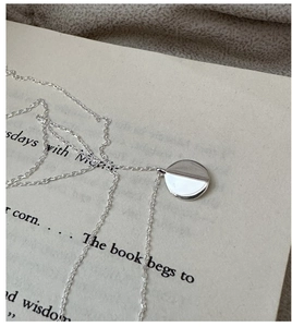 Macro detail of minimalist S925 sterling silver round pendant on an O-chain necklace