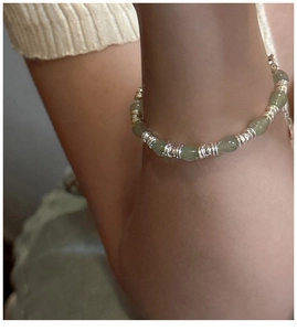 Détail de perles gouttes vert clair et d'entretoises en argent sur un bracelet perlé