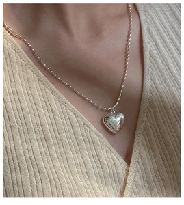Detail of S925 silver hollow heart pendant on a delicate bead chain worn by a model