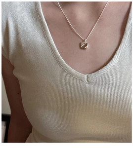 Minimalist square silver pendant on a thin chain worn by a model against a soft knit top