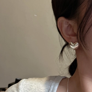 Elegant polished S925 sterling silver heart-shaped stud earrings worn by a model