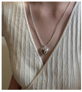 Close-up of minimalist S925 sterling silver hollow heart pendant on a woman neck