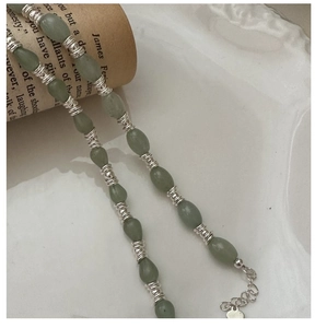 Gros plan d'un bracelet en argent S925 avec perles en pierre vert olive et cœur doré