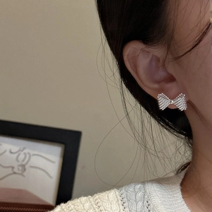 Minimalist S925 sterling silver bow earrings with a unique textured beaded finish on model