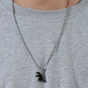 Dettaglio della catena d'argento con un ciondolo a forma di dinosauro nero dallo stile minimal