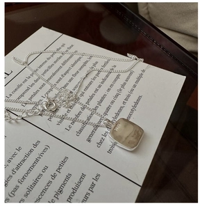 Macro detail of S925 sterling silver stamp on minimalist square pendant necklace